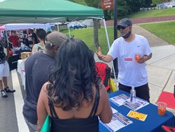An outreach liaison talks to community members while tabling at an event.