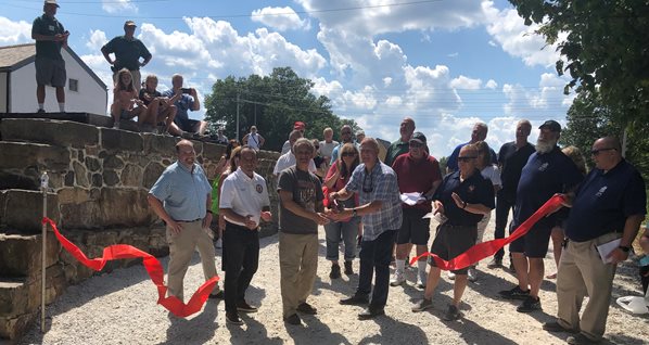 A group of officials cuts a ribbon near the Morris Canal Lock 2 East restoration project in Wharton Borough, NJ.