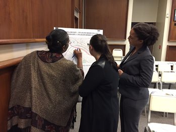 Three woman look at a map of a project study area.